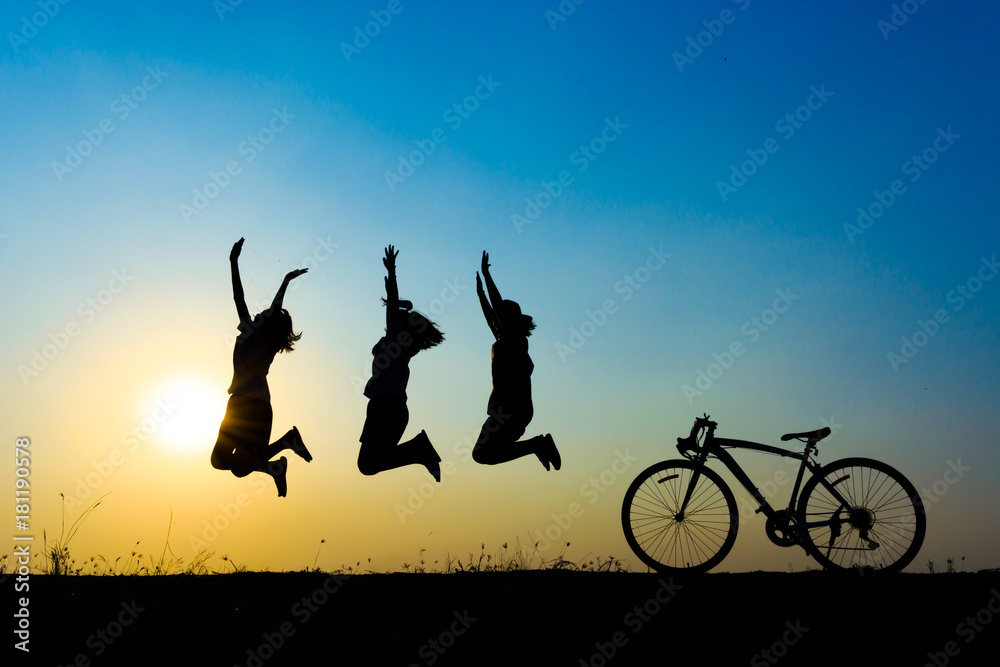 silhouette of young woman jumping on sunset sky with bicycle on the prairie at yellow evening horizon sea yellow sunset heaven background outdoor.
