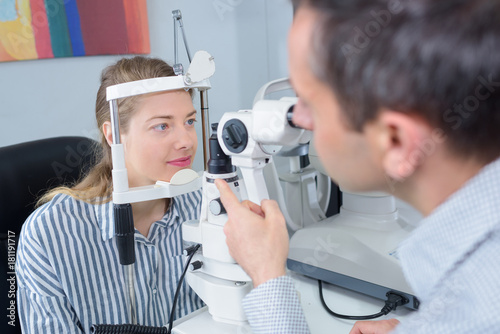 male optician in surgery giving woman eye test