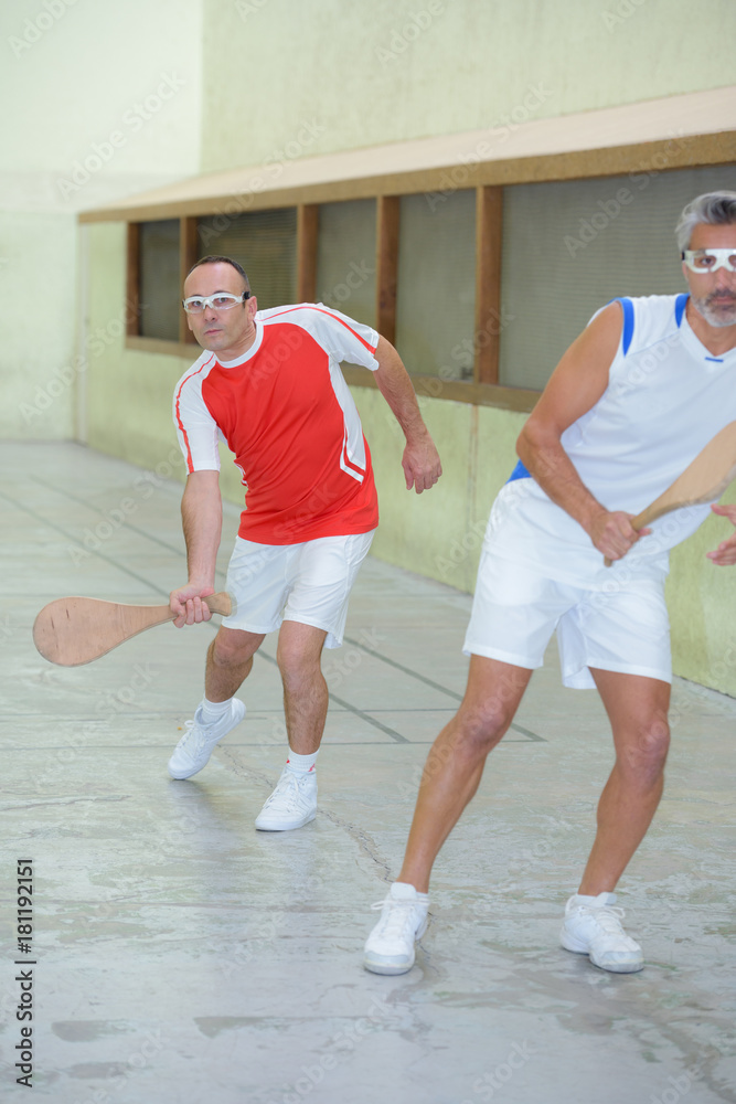 Men playing squash with wooden racket