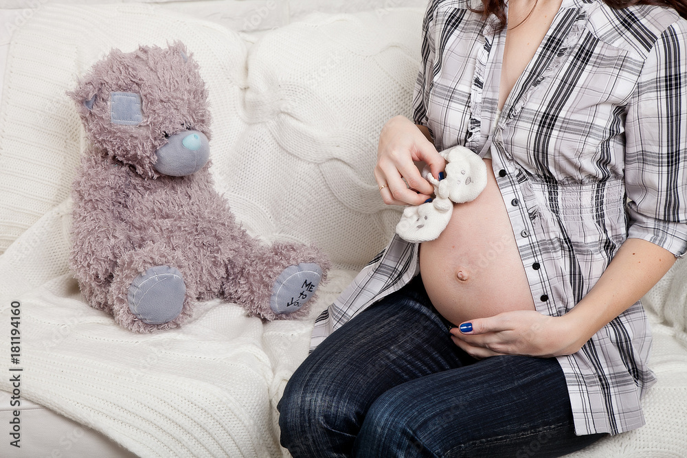 tummy of a pregnant woman with shoes for a newborn girl in hands tummy of a pregnant woman with shoes for a newborn girl in hands