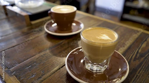 Cortado or macchiato served at a coffee bar cafe with a cream drawing on top in a clear glass. photo