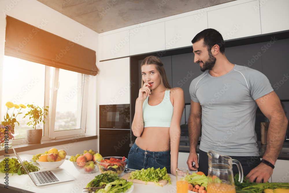A couple is preparing a salad for breakfast. A man and a woman are posing in the cooking process. A couple is preparing a salad for breakfast. A man and a woman are posing in the cooking process.