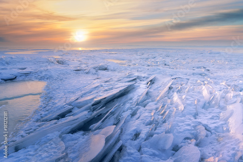 winter dawn on the frozen lake   whimsical snow patterns in the rays of dawn