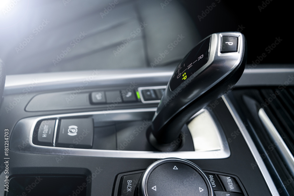 Automatic gear stick (transmission) of a modern car, multimedia and navigation control buttons. Car interior details. Transmission shift. Soft lighting