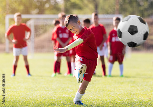 Fototapeta Chłopiec kopie futbol na boisku sportowym