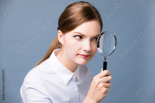 Young woman looking at something with magnifying glass.