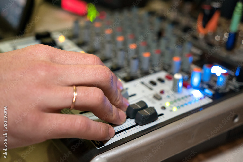 DJ working on a audiomixer at a nightclub. Close-up of hands adjusting quality of music using a knobs of the audio mixer DJ working on a audiomixer at a nightclub. Close-up of hands adjusting quality of music using a knobs of the audio mixer