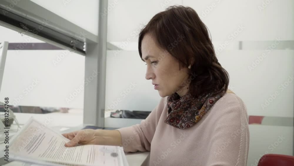 A woman receives documents for real estate in the registration chamber. A woman receives documents in a multifunctional center. A woman receives documents for real estate in the registration chamber. A woman receives documents in a multifunctional center.