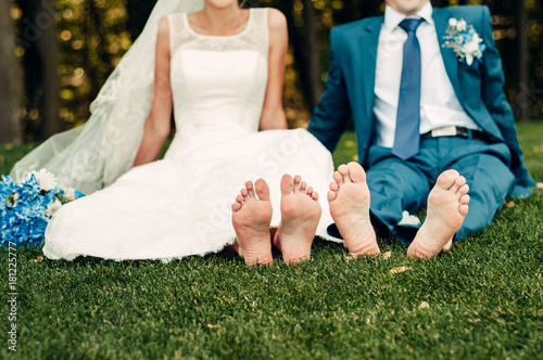 Fotografi barefooted young fair-haired bride and her fiance sits on the grass in an exotic