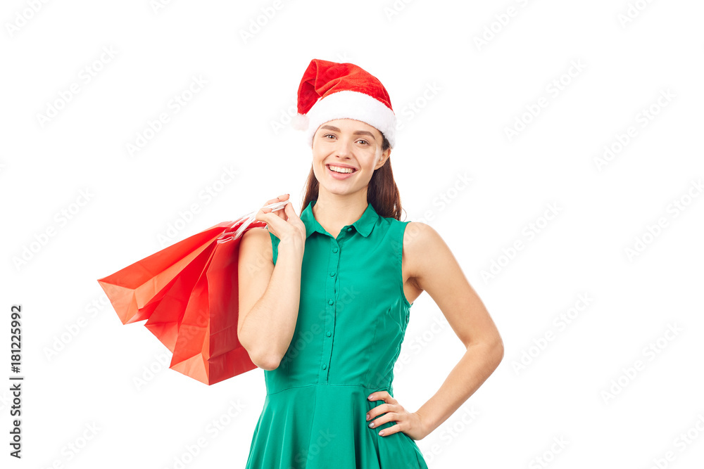 Studio portrait of young woman in Santa hat posing with shopping bags on white background Studio portrait of young woman in Santa hat posing with shopping bags on white background