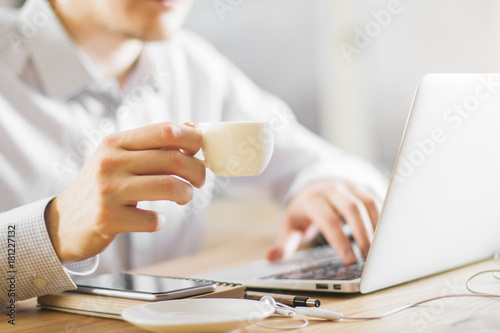 Man drinking coffee using laptop