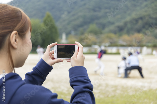 野球の試合をスマホで撮影する野球部マネージャー