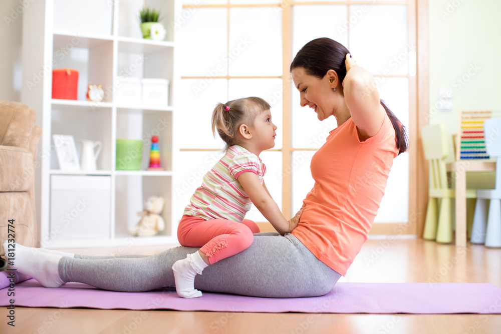 Momr and her child daughter are engaged in fitness, yoga, exercise at home. Kid and woman swing press on stomach. Momr and her child daughter are engaged in fitness, yoga, exercise at home. Kid and woman swing press on stomach.