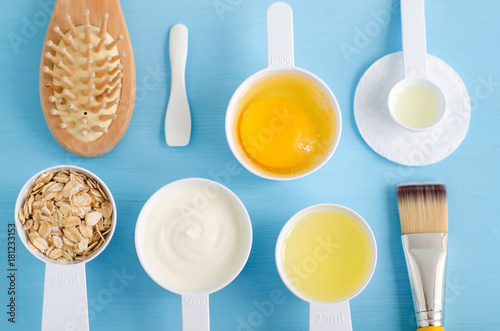 Sour cream (greek yogurt), raw egg, rolled oats and olive oil in a small plastic scoops - ingredients for preparing diy hair and facial masks, scrubs and moisturizers. Homemade cosmetics. 