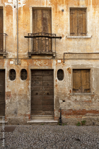 Withered facade with window of an old Italian town house. Cracks in the wall. Byzantine frame.
