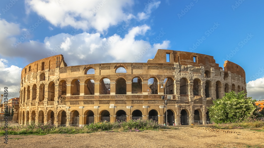 Fototapeta premium Sunset at the Colosseum with clouds, with no people, Flavian Amphitheatre, the largest amphitheater in the world and one of the symbols of Italy and Rome.