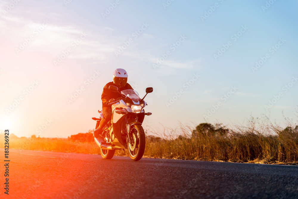 Obraz premium man riding motorcycle on sunset
