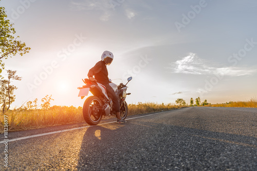 Man on motorcycle on the road during sunset
