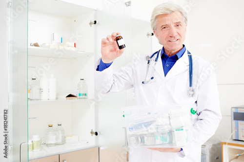 Mature man in uniform showing small bottle with pills in clinics