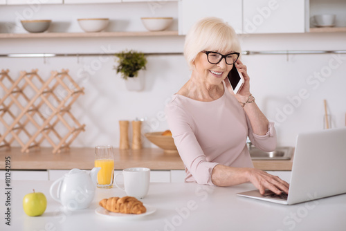 Joyful elderly woman standing in the kitchen