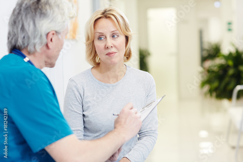 Mid-aged blonde having talk with doctor making prescriptions for her