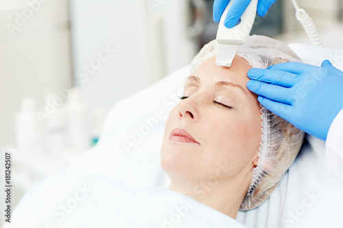 Woman with aging skin having facial care procedure while visiting beautician