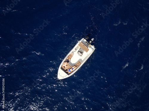 Aerial survey of a couple on a boat sunbathe together on a warm summer day © vladstar