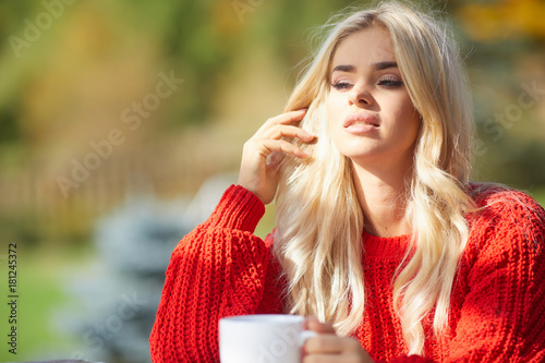 Beautiful blonde woman drinking a cup of coffee in a terrace.