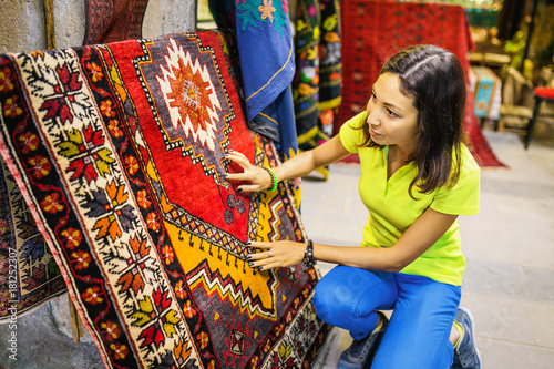 Canvas Print woman chooses oriental carpet at market in Turkey