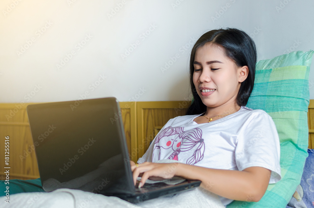 happy casual beautiful Asian woman working on a laptop notebook sleep on the bed in the house. happy casual beautiful Asian woman working on a laptop notebook sleep on the bed in the house.