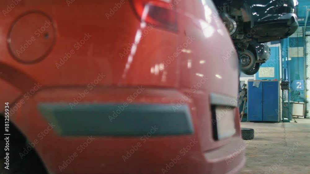 Mechanic male in automobile garage working under bottom of a car Mechanic male in automobile garage working under bottom of a car