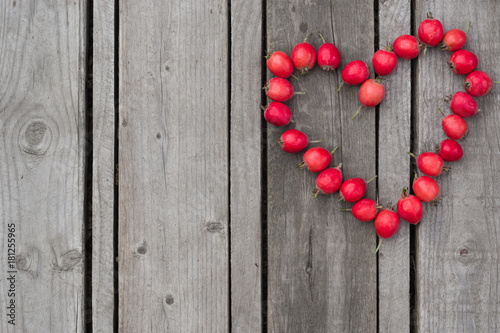 Red heart of hawthorn berries on a wooden background