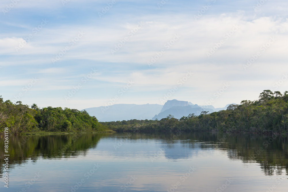 Reflections of sky and trees on the waters of the Autana river, in the amazon jungle