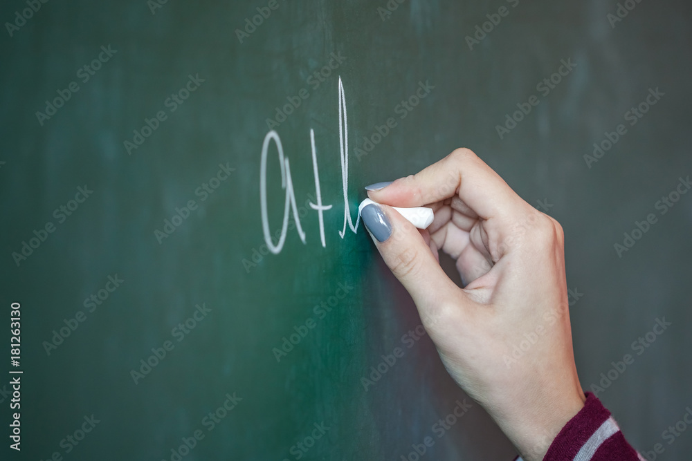 girl with chalk in her hand solves a mathematical problem on the blackboard