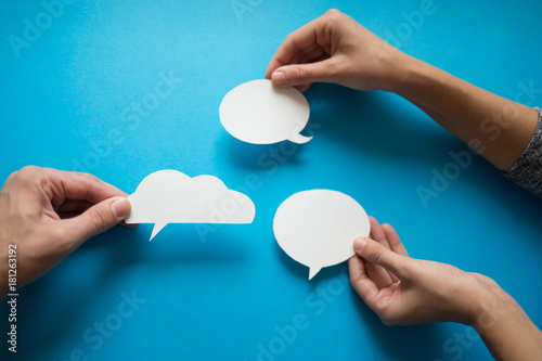 Hands holding empty speech balloon.