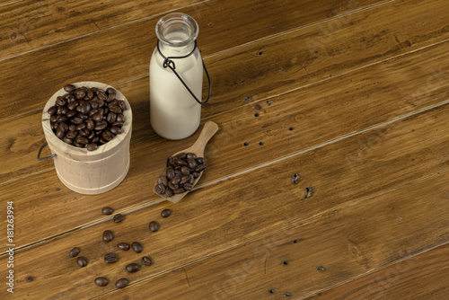 Coffee bean grain ,bottle of milk and sack fabrice board on brown wood table background , include copyspace for add text or graphic in advertise or marketing content photo