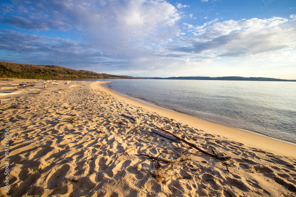 Obraz premium Summer Day At The Beach Background. Warm sunny summer day on the shore of Lake Superior with a wide sandy beach and blue water horizon. Horizontal orientation wide angle with copy space.