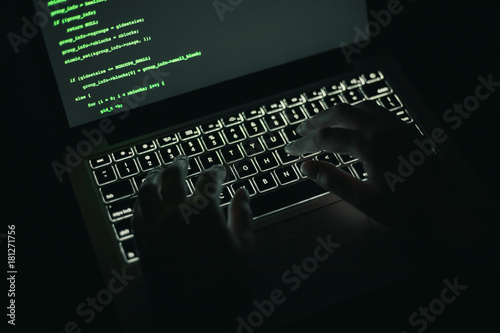 Cyber crime concept: hands of a person hacking on laptop in the darkness