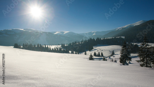 Winter landscape in mountains on background of blue sky and sun