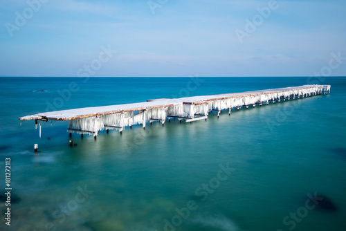 Frozen fishing pier with hanging icicles in a sunny winter day © diyanadimitrova