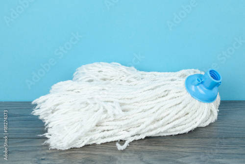A cotton  head of classic mop on  wooden floor against blue wall