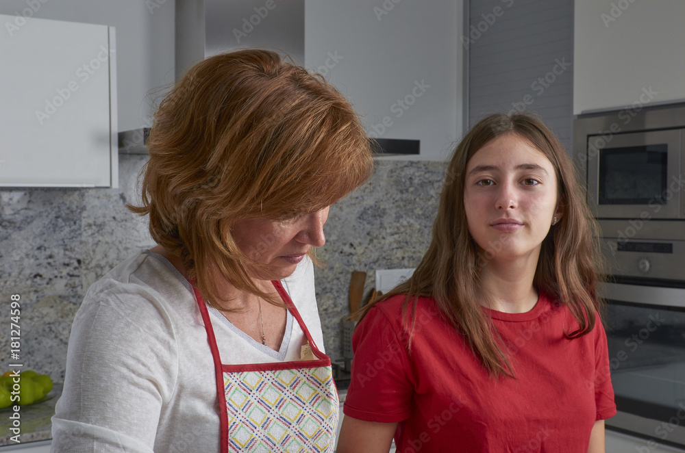 Mother and her teenage daughter are cooking together in the kitchen, prepare a salad. Vegan Family. Mother and her teenage daughter are cooking together in the kitchen, prepare a salad. Vegan Family.