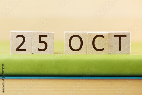 Wooden cube shape calendar for OCT 29 on green book, table.   photo