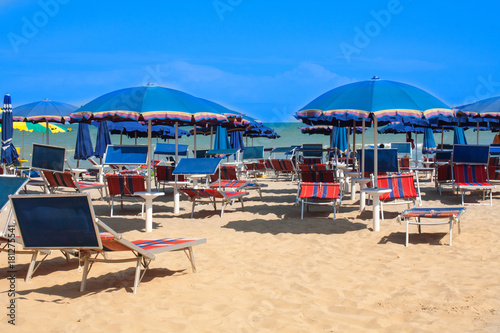 Adriatic Sea coast view. Seashore of Italy  summer umbrellas on sandy beach with clouds on horizon.
