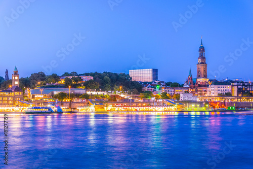 View of the Elbe riverside with the hamburger landungsbruecken building, saint michaelis church and the bismarck monument in Germany during sunset. photo