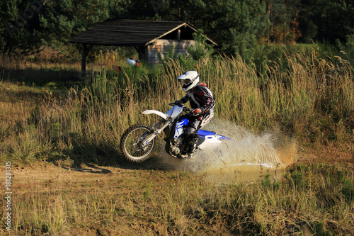 Enduro, motocyklista na motorze crossowym w kałuży.