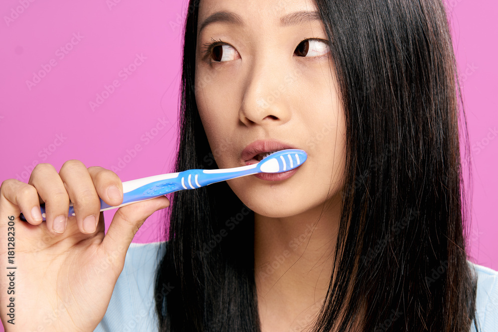 Teeth care, a woman cleans teeth, oral hygiene, healthy teeth, a woman on a pink background Teeth care, a woman cleans teeth, oral hygiene, healthy teeth, a woman on a pink background