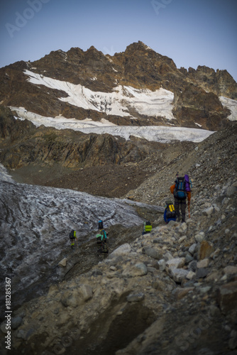 A group of hiking tourists go along the glacier to the mountain pass. The weather facilitates complex movement in the high-mountainous area. Travelling in the Caucasian Mountains in Georgia