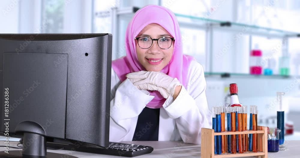 Cute female muslim scientist smiling at the camera while sitting in the ...