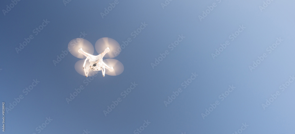 Fotografie White UAV Quadcopter Drone in Flight Blue Sky